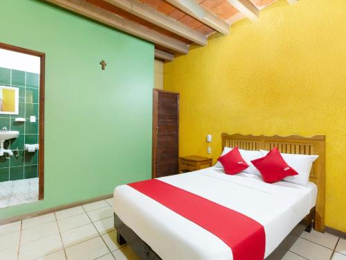 a bedroom with a large bed with red pillows at Hotel Posada San Rafael in Oaxaca City