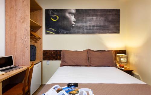 a bedroom with a bed and a desk with a computer at Pousada Bahia Bacana in Morro de São Paulo