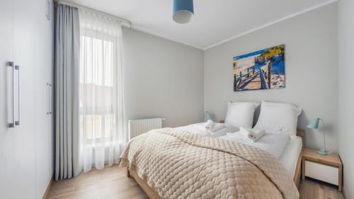 een witte slaapkamer met een bed en een raam bij Apartament w Rezydencji Park in Mielno