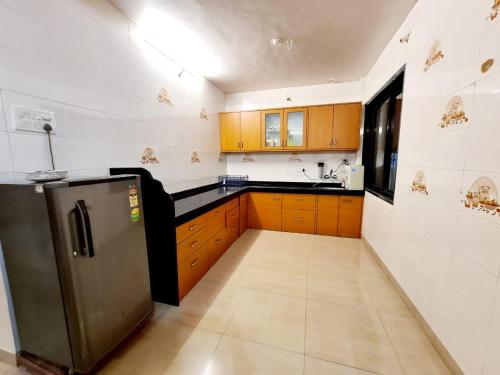 a kitchen with wooden cabinets and a stainless steel refrigerator at Nilgiri Villa with Swimming Pool in Mahabaleshwar