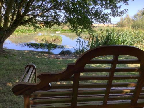 a wooden bench sitting in front of a pond at The Retreat, Clematis cottages, Stamford in Stamford