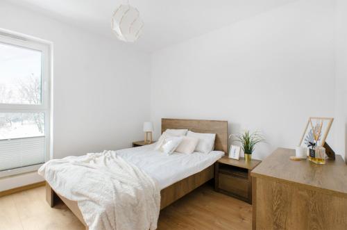een witte slaapkamer met een bed en een raam bij GoldAparts Gdańska in Łódź