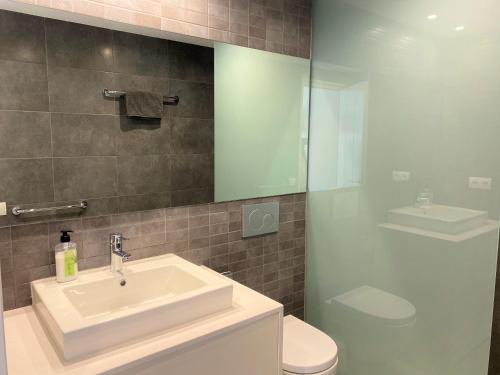 a bathroom with a sink and a toilet and a mirror at TÒRTORA - Casa en el centro con vistas al mar in Cadaqués