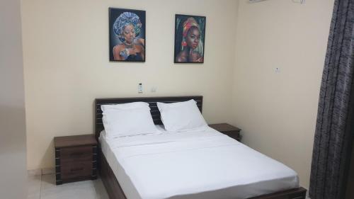 a bed in a room with three pictures on the wall at Aimé Anaïs in Abaga