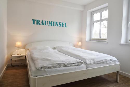 a white bed in a room with a sign on the wall at Stadtwohnung 8 in Wyk auf Föhr