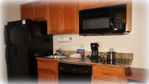 a kitchen with a black refrigerator and a sink at Candlewood Suites Fredericksburg, an IHG Hotel in Fredericksburg