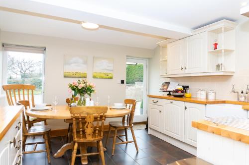 a kitchen with white cabinets and a wooden table and chairs at Stoney Moat in Shrewsbury