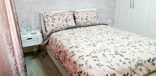 a bedroom with a bed with a floral bedspread at Stunning Room with Large Private Bathroom in Derby