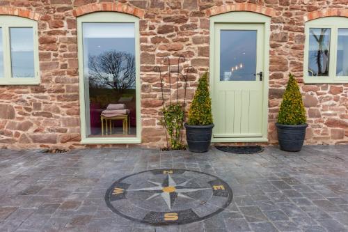 a stone building with a door and potted trees at The Patches in Shrewsbury