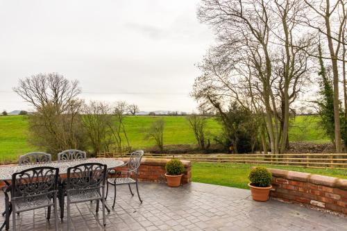 a patio with a table and chairs and a field at The Patches in Shrewsbury