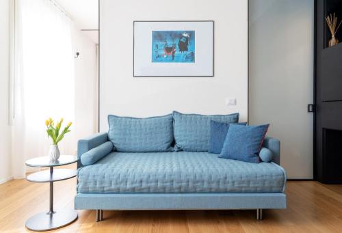 a blue couch in a living room with a table at BMORE Duomo - Luxury Apartments near Duomo in Milan