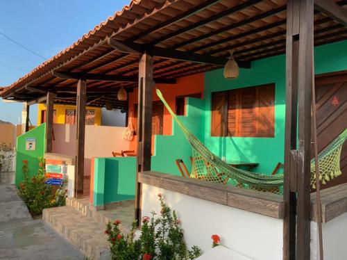 Pousada Villa Galinhos في غالينوس: منزل ملون مع أرجوحة عليه