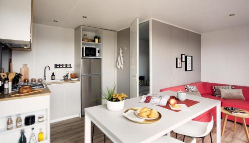 een keuken en een woonkamer met een witte tafel bij CAMPING LE SOLEIL D'OR in Vendays-Montalivet