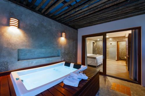 a large bath tub in a room with a bedroom at Pousada Bahia Bacana in Morro de São Paulo