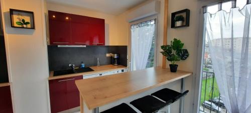 d'une cuisine avec des placards rouges, un évier et une fenêtre. dans l'établissement T3 entièrement rénové - 5 couchages, à Lourdes