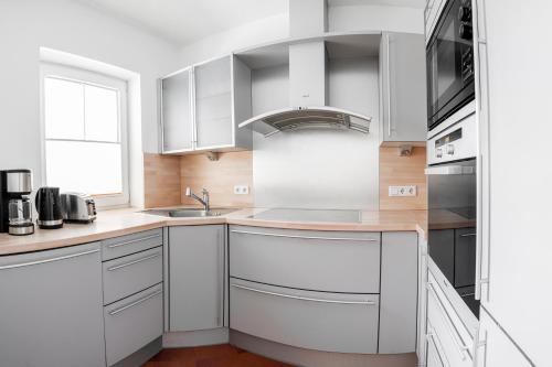 a kitchen with white cabinets and a sink at Landhaus Martinus in Sölden