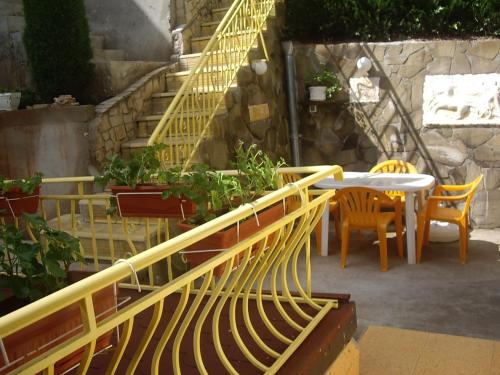 a yellow stair railing with a table and chairs at Guest House Rusalka in Shipkovo