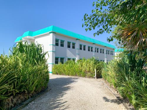 a white building with a green roof at Best Western Grand Baymen Gardens in San Pedro