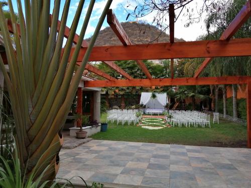 a patio with white chairs and a wooden pergola at Ex Hacienda Santa Elena in Atlixco