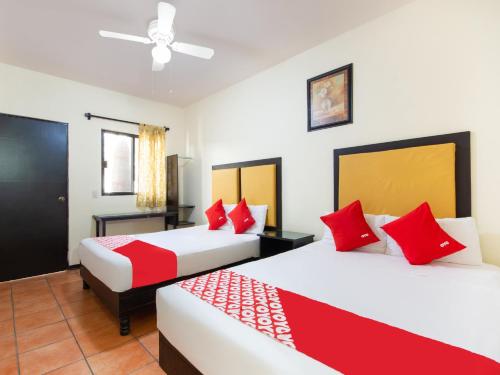 two beds in a hotel room with red pillows at HOTELES CATEDRAL Torreón in Torreón