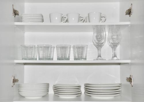 a shelf filled with glasses and plates and wine glasses at Cozy Stays Cayala Apartments 4 in Guatemala