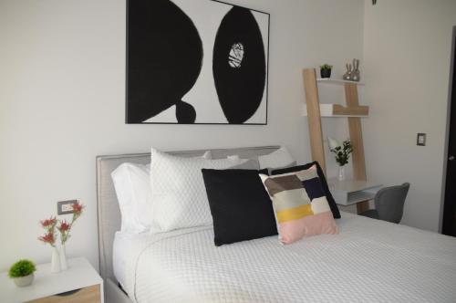 a bedroom with a bed with black and white pillows at Cozy Stays Cayala Apartments 4 in Guatemala