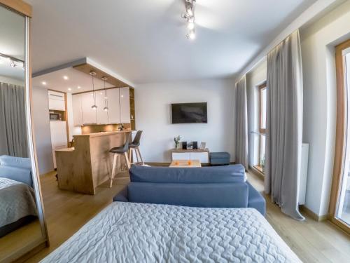 a bedroom with a blue couch and a kitchen at ApArt Bulwary Wrocław in Wrocław