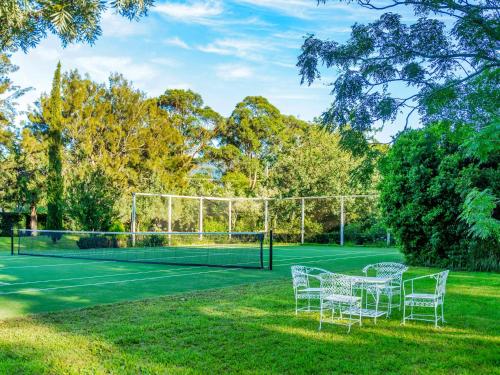 a tennis court with chairs and a net at Milhouse Berry in Berry