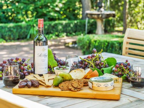 a bottle of wine sitting on a table with cheese and grapes at Milhouse Berry in Berry