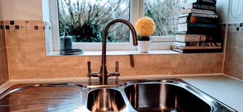 a sink in a kitchen with a window and books at Brookside 2BR Flat Oxford City Centre Free Parking in Oxford