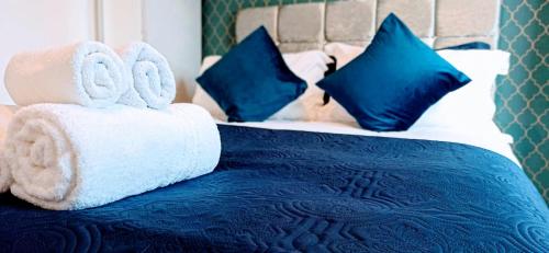a blue and white bed with towels and pillows at Brookside 2BR Flat Oxford City Centre Free Parking in Oxford