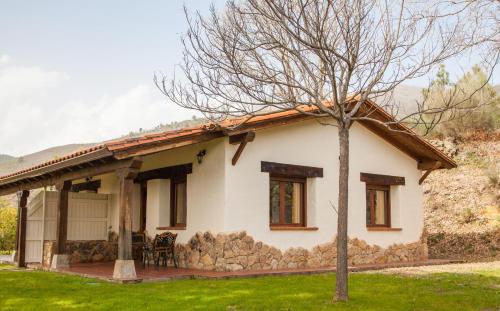 una pequeña casa blanca con un árbol delante en Finca La Sayuela, en El Raso