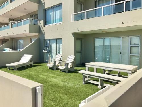 un patio avec des chaises et une table de pique-nique et un bâtiment dans l'établissement Voir la Mer - Blouberg Beach, à Bloubergstrand