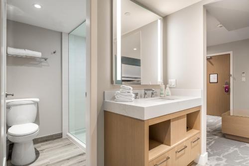 a bathroom with a sink and a toilet and a mirror at Coast Tsawwassen Inn in Delta