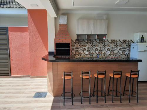 a kitchen with a counter with four bar stools at Recanto Matheus Morotti MM in Maringá