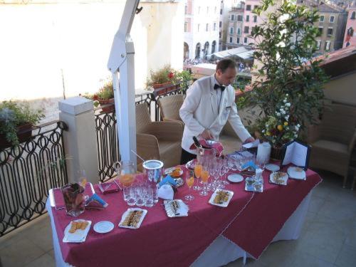 a man is standing next to a table with glasses at Foscari Palace in Venice