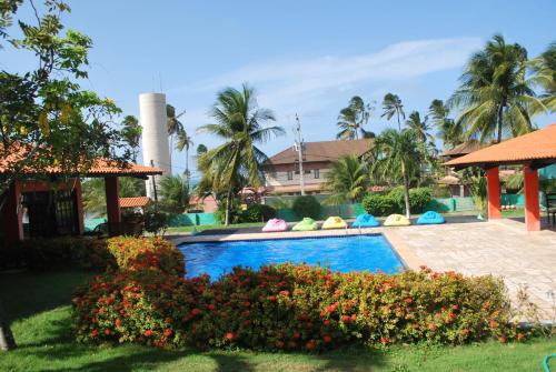 uma piscina num resort com palmeiras e um edifício em Sunshine Cumbuco em Cumbuco