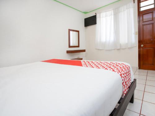 a bedroom with a white bed with a red and white blanket at OYO Hotel Nachancan in Chetumal
