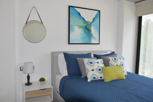 a bedroom with a blue bed and a mirror at Cozy Stays Cayala Apartments 4 in Guatemala