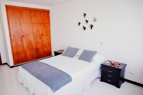 Apartamento Lorenita في كارتاهينا دي اندياس: غرفة نوم مع سرير وخزانة وطيور على الحائط