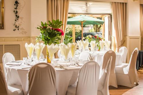 uma mesa com mesas e cadeiras brancas e um guarda-sol verde em The Castle Hotel em Llandovery