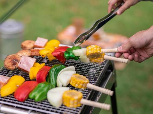 a person cooking food on a grill with tongs at Garni MonyaMonya/ガルニモニャモニャ in Hokuto