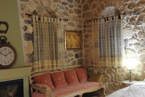 a living room with a couch and a clock at Armonia Hotel in Kefalari