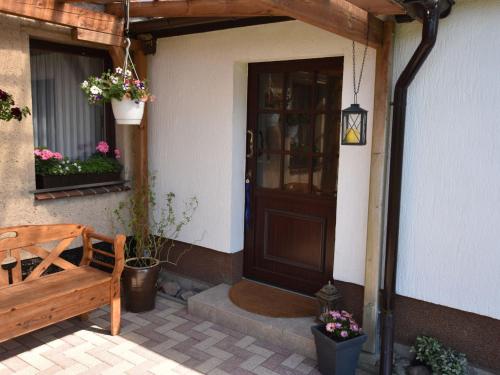 a door of a house with a bench and flowers at Gemütliche Ferienwohnung mit Garten in Robertsdorf in Blowatz