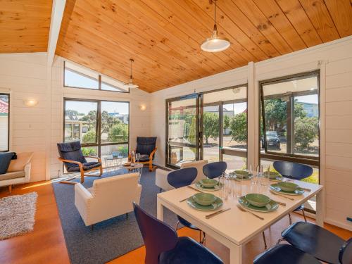 a living room with a table and chairs at Champion Bach - Pauanui Holiday Home in Pauanui