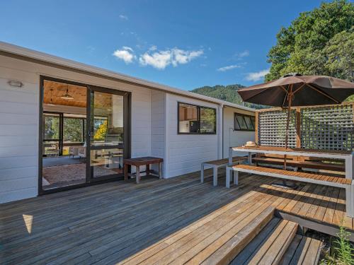 a deck with a bench and an umbrella at Champion Bach - Pauanui Holiday Home in Pauanui