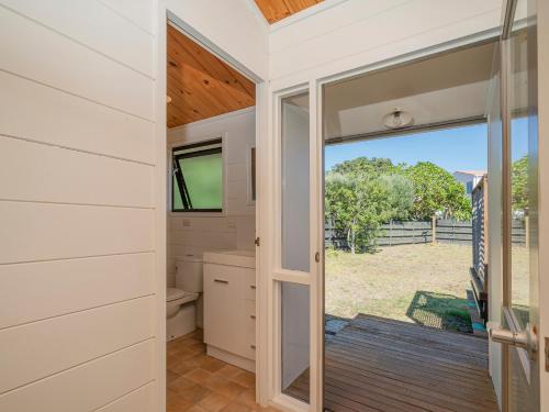 a bathroom with a toilet and a sliding glass door at Champion Bach - Pauanui Holiday Home in Pauanui