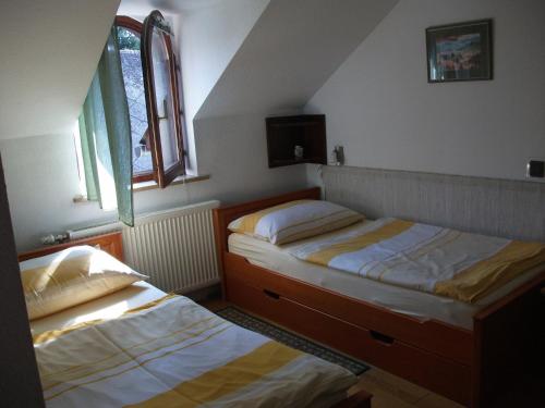 two beds in a room with two windows at Ria Panzio in Esztergom