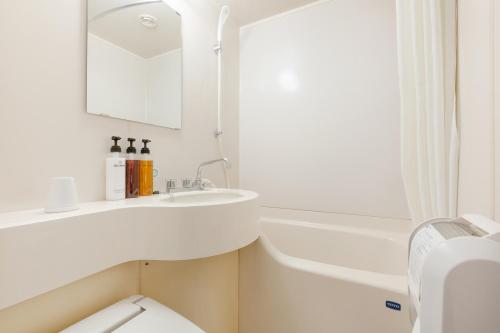 a white bathroom with a sink and a bath tub at The OneFive Okayama in Okayama