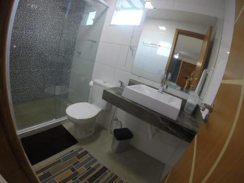 a bathroom with a sink and a shower and a toilet at Suites Golfo in Abraão